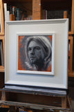 Oil painting of Kurt Cobain from Nivana framed in white. Photographed on the artist's easel.